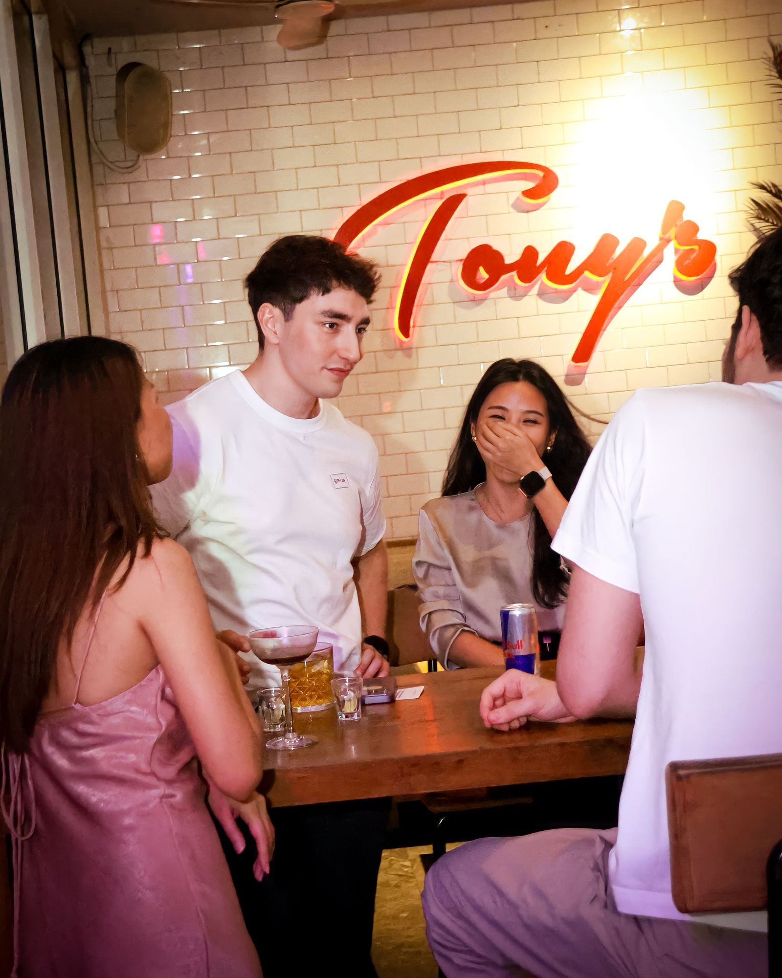 Guests talking and laughing around a table under the Tony's sign