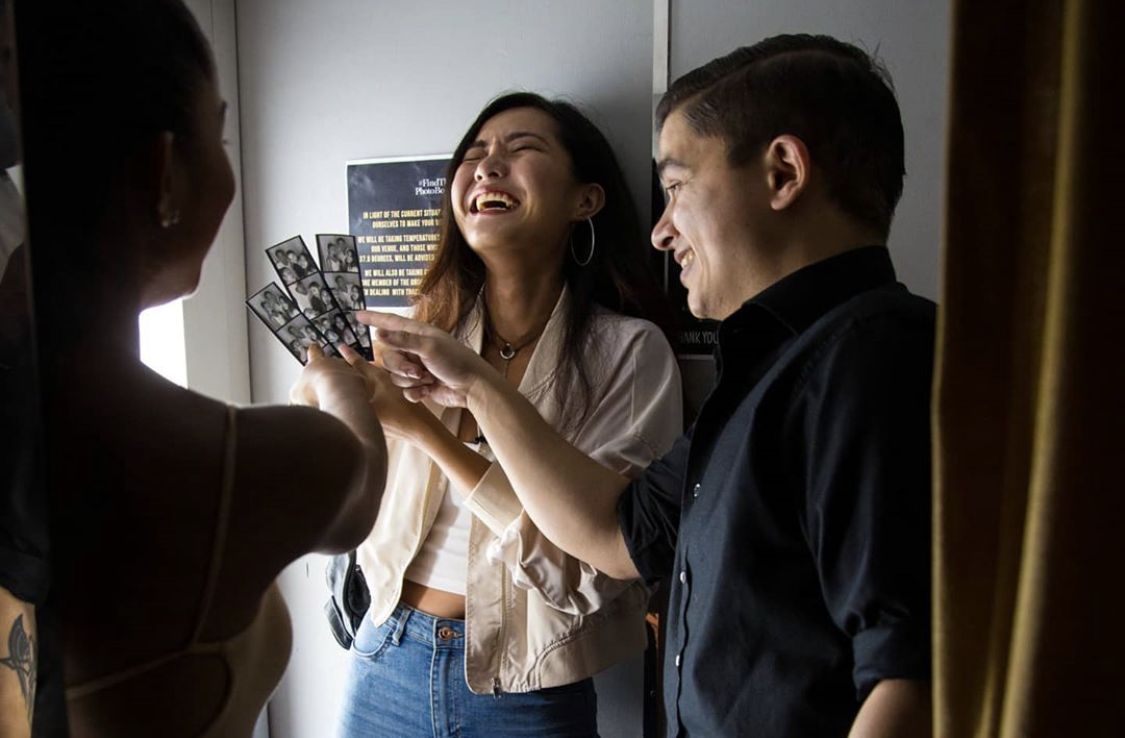 Two guests laughing together while sharing photo-booth strips